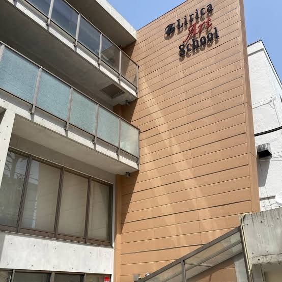 青空の下のリリカ・アートスクールの外観。れんが色の壁にLirica Art Schoolのロゴ